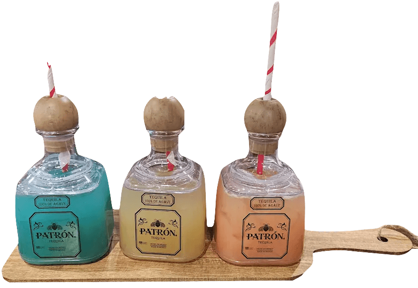 Three margaritas served in Patrón bottles on a wooden paddle